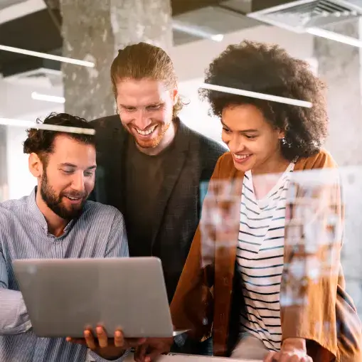 Foto de três pessoas, dois homens e uma mulher. todos em pé observando um laptop que um dos homens tem na mão.